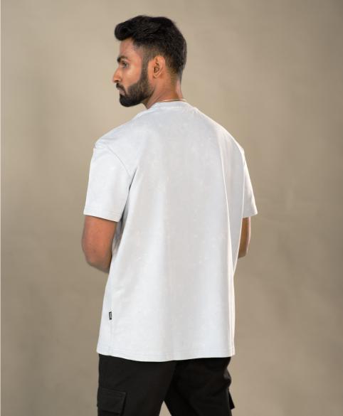 Man wearing a white t-shirt and black pants against a beige background