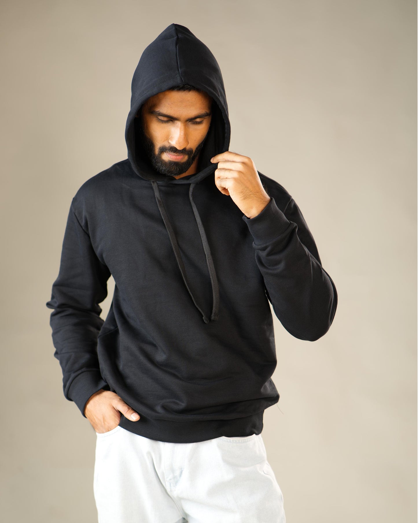 Man wearing a black hoodie against a beige background