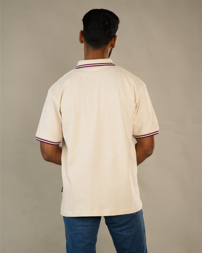 Man wearing a beige polo shirt with red and white trim on a plain background