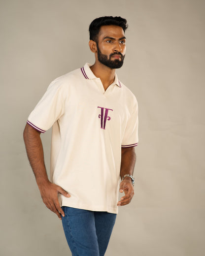 Man wearing a cream polo shirt with a logo on a plain background