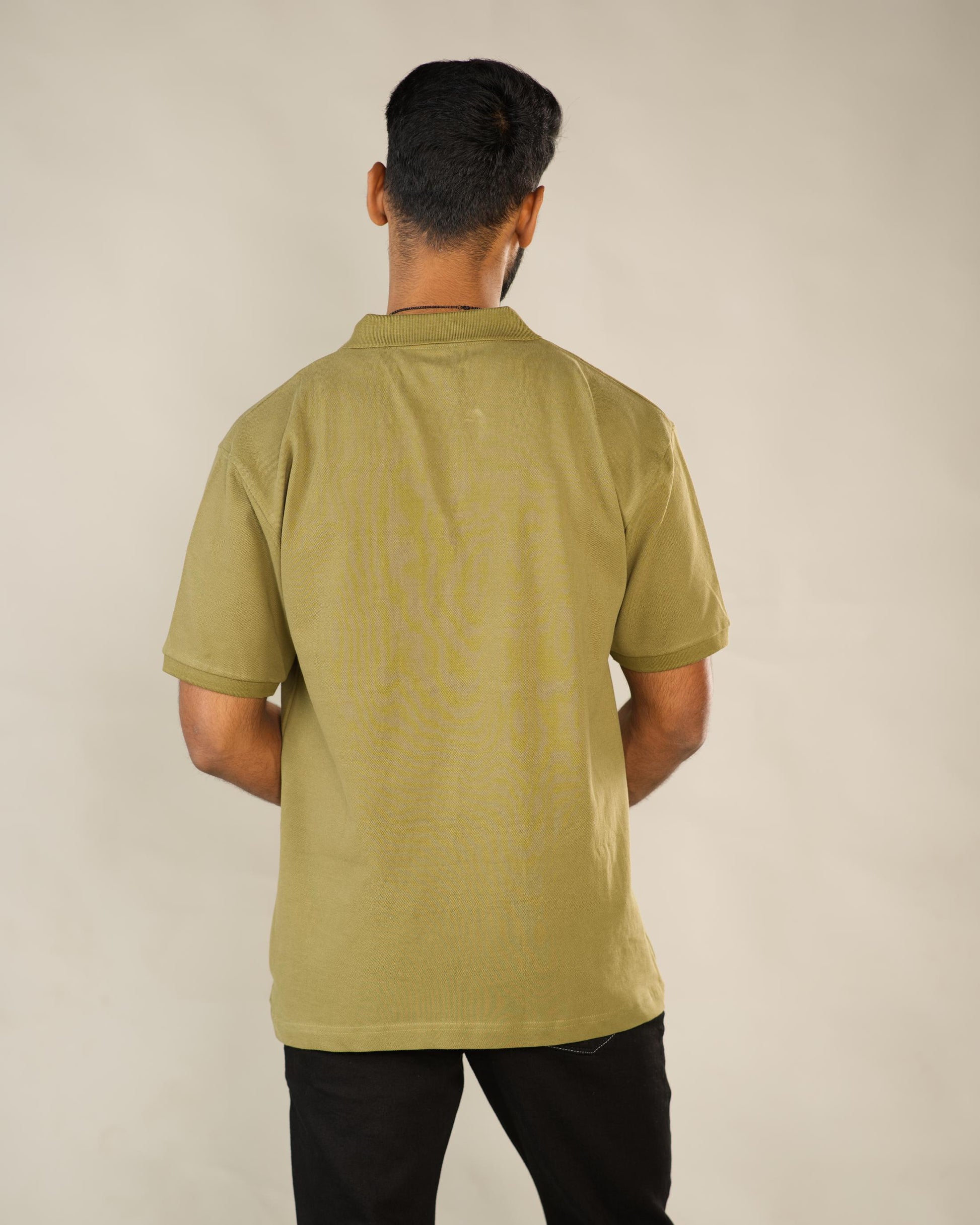 Person wearing a green polo shirt against a beige background - Image 4