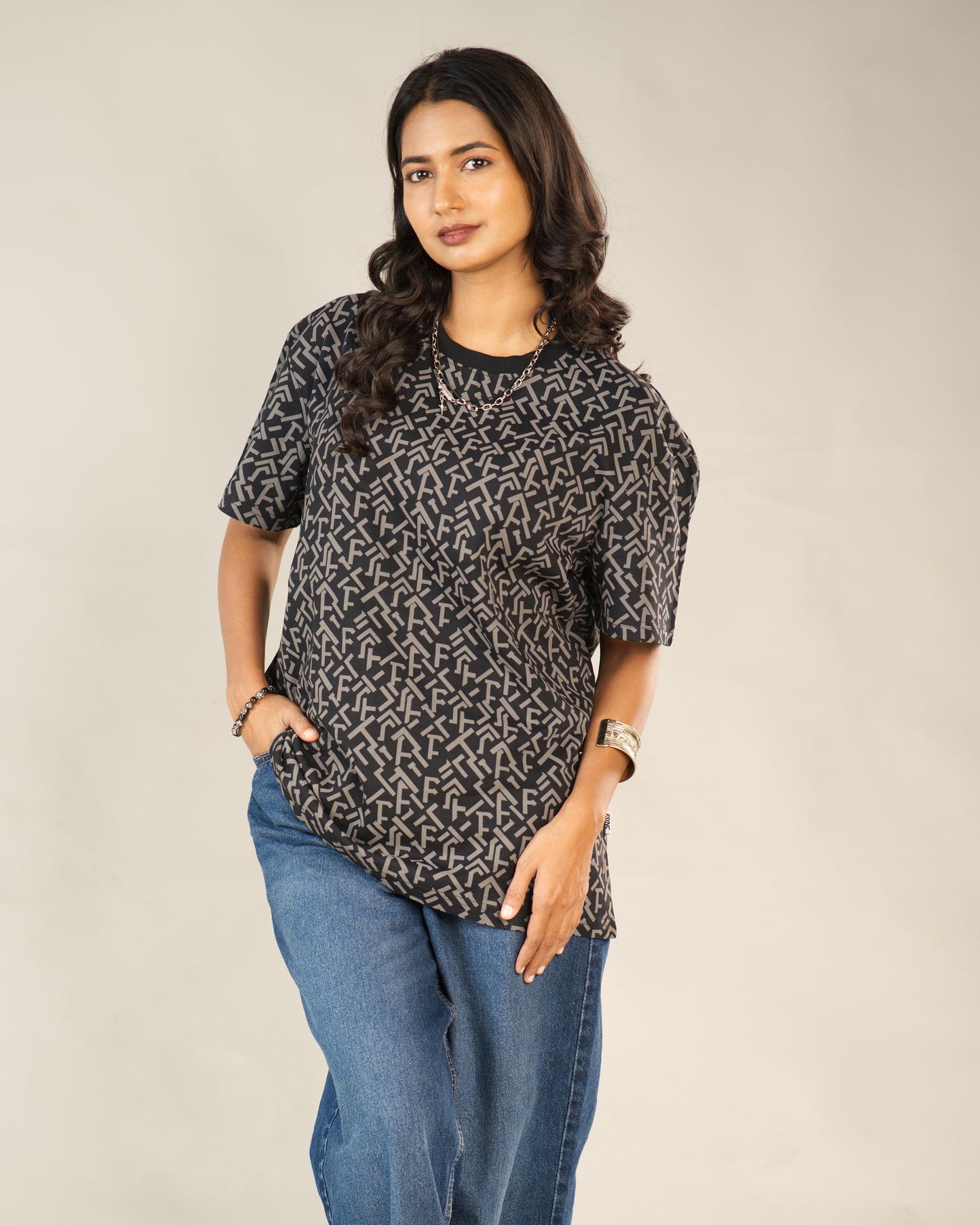 Woman wearing a black patterned shirt and blue jeans on a beige background