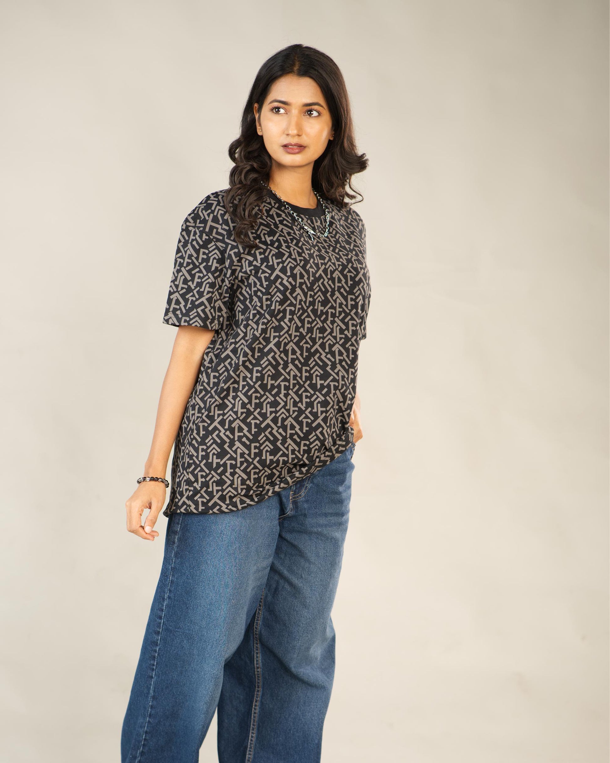 Woman wearing a patterned top and blue jeans against a plain background - Image 3