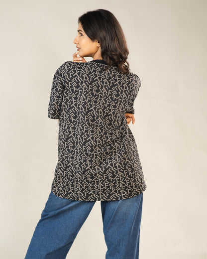 Woman wearing a patterned black and white top with blue pants on a beige background