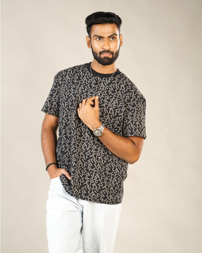 Man wearing a black patterned t-shirt and white pants against a beige background