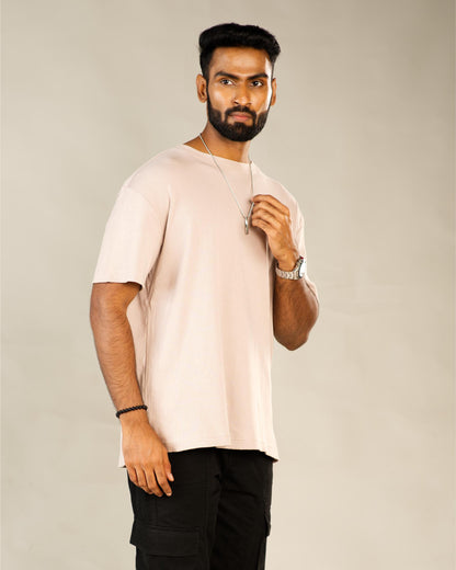Man wearing a light pink t-shirt and black pants against a plain background