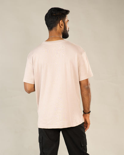 Man wearing a light pink t-shirt and black pants against a plain background