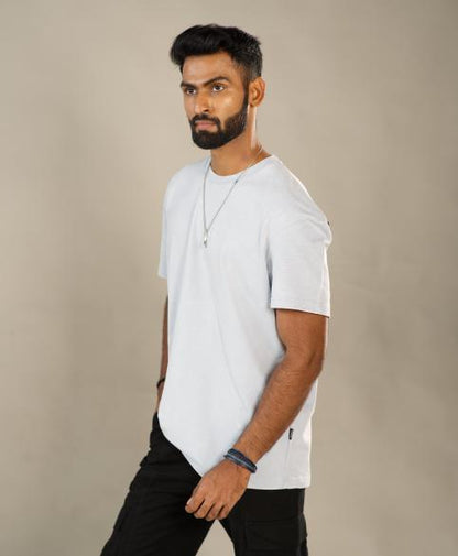 Man wearing a white t-shirt and black pants against a beige background