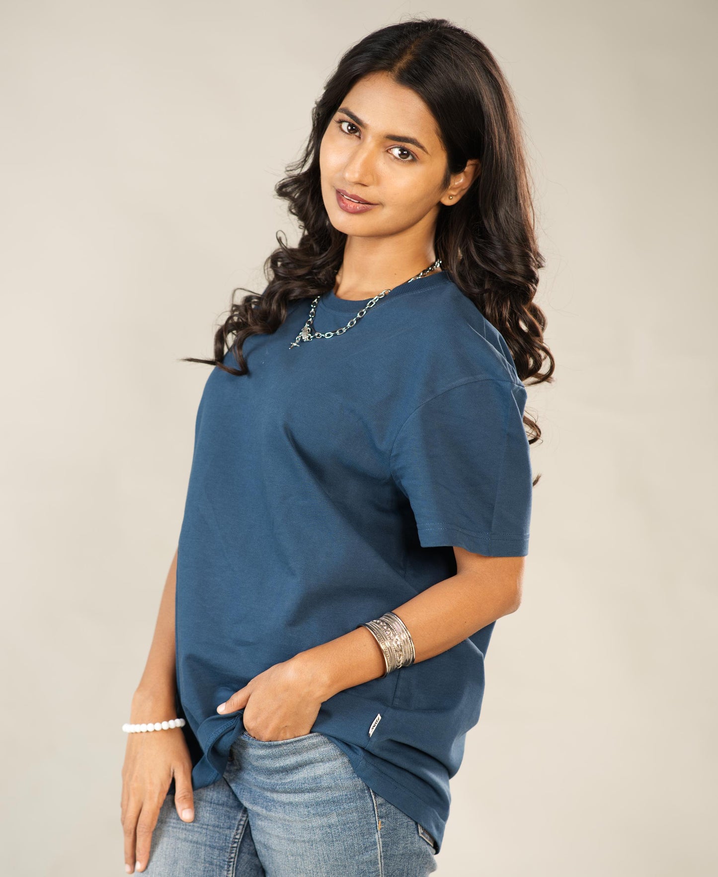 Woman wearing a blue shirt and jeans against a plain background