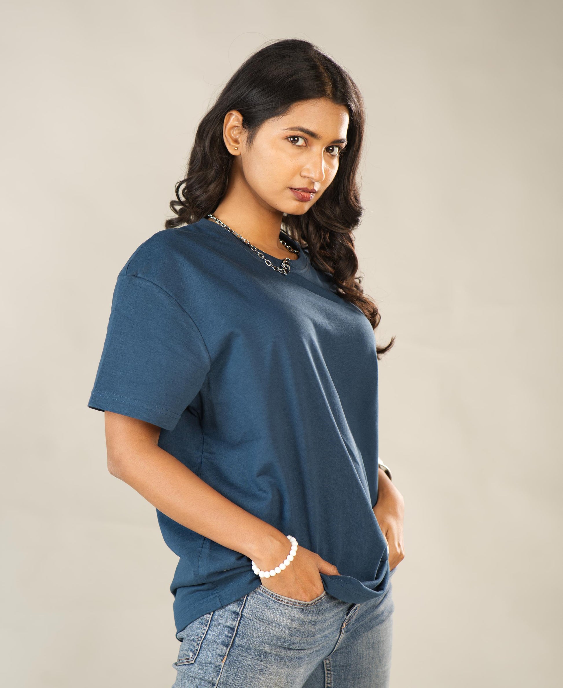 Woman wearing a blue t-shirt and jeans against a plain background - Image 6