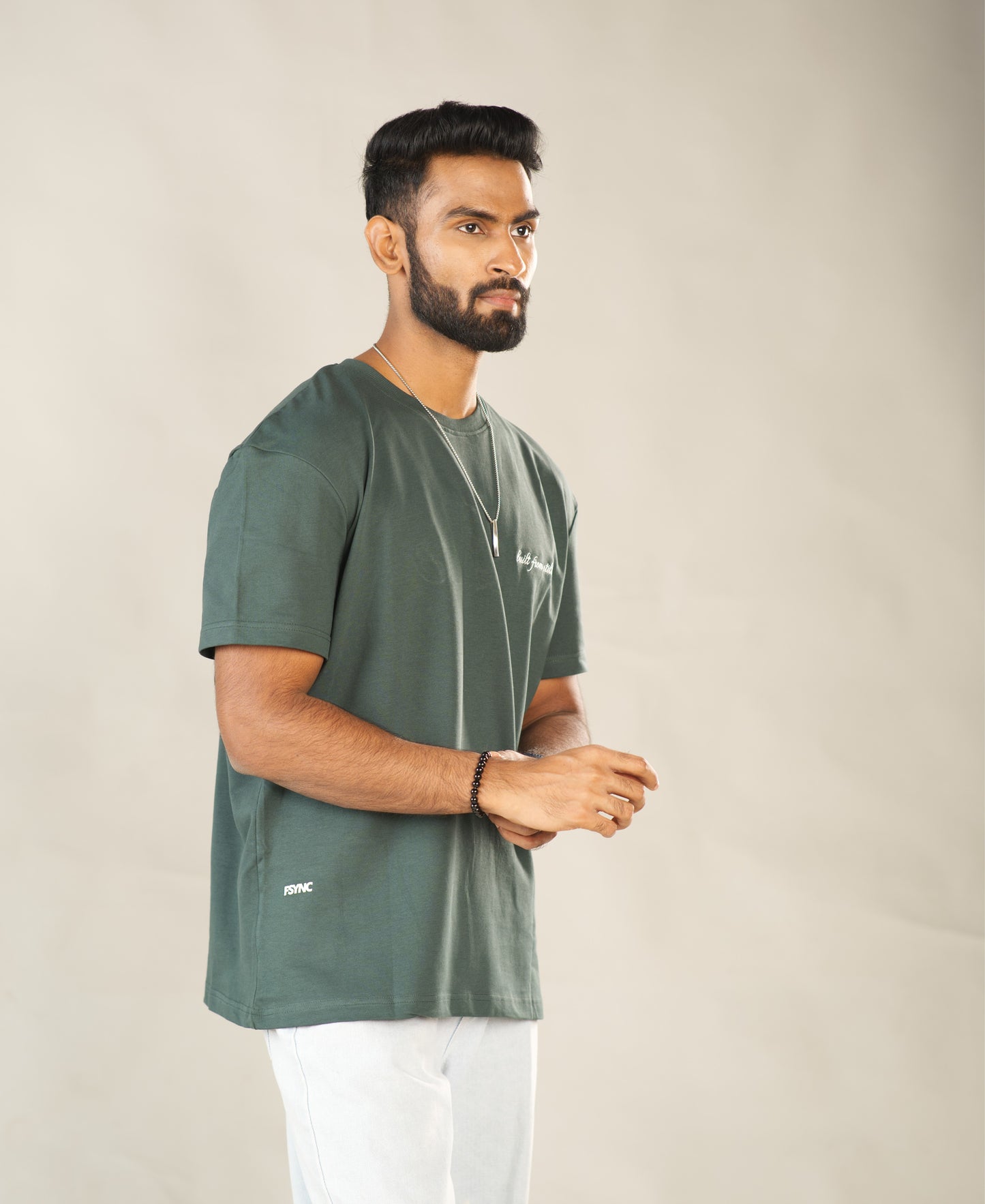 Man wearing a green t-shirt with a logo on a beige background