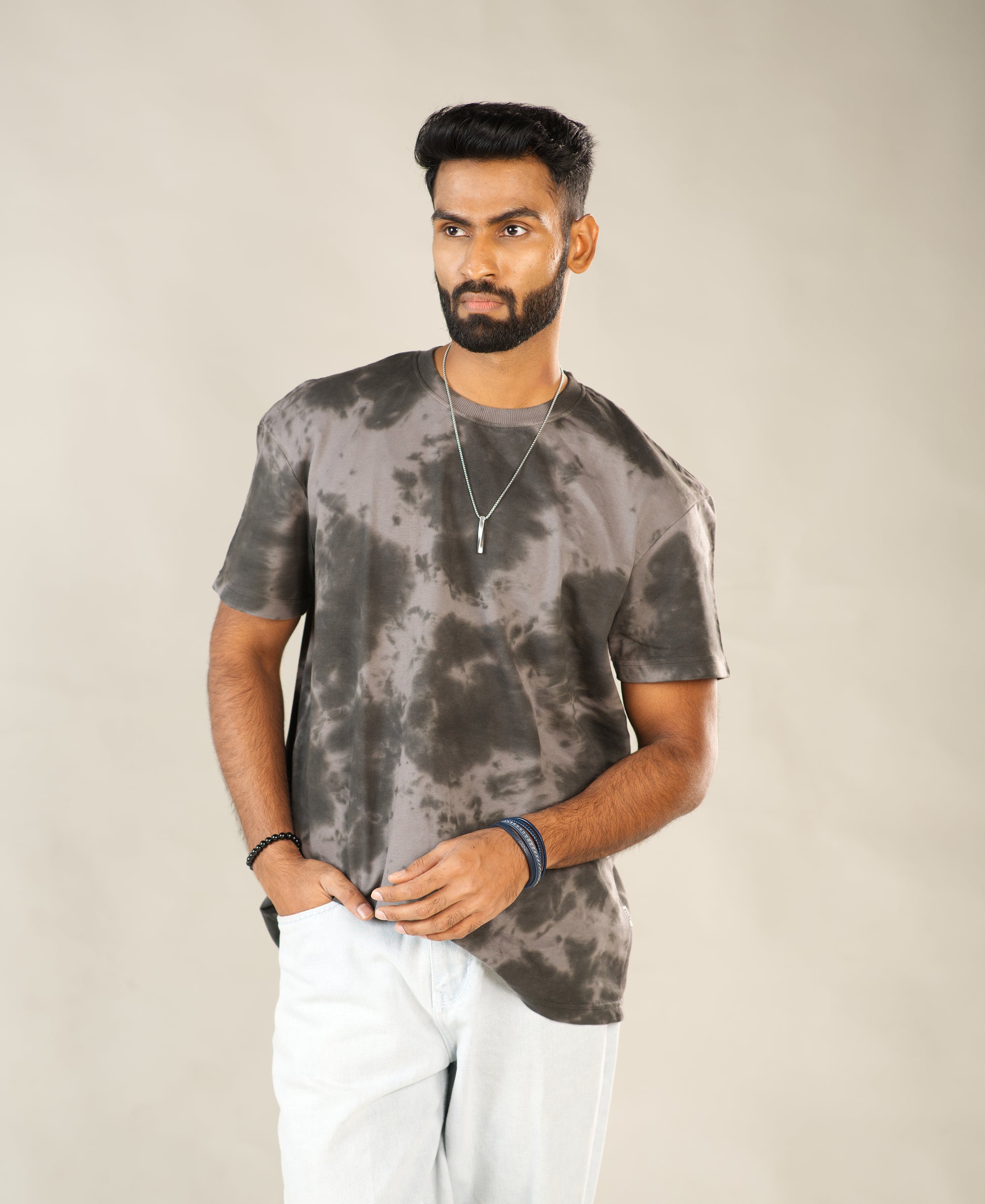 Man wearing a gray tie-dye t-shirt and white pants against a beige background - Image 2