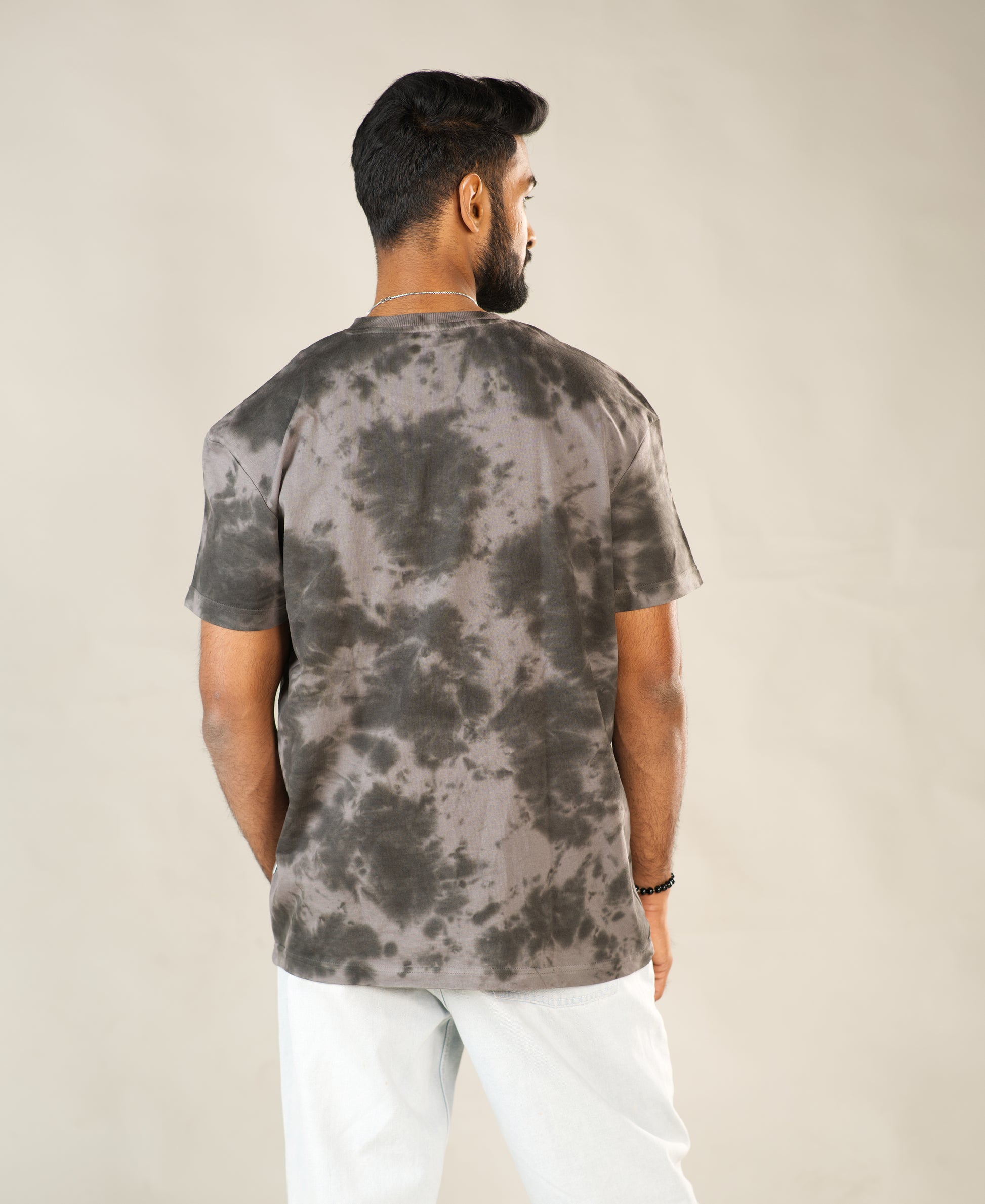 Man wearing a tie-dye t-shirt and white pants on a plain background - Image 8